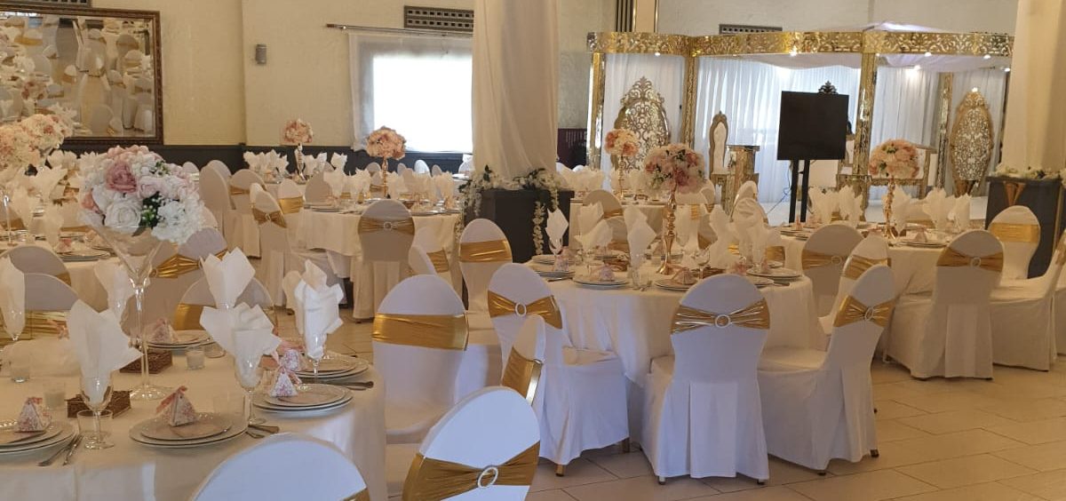 Grupo de sillas blancas dispuestas en un área al aire libre rodeada de árboles.
